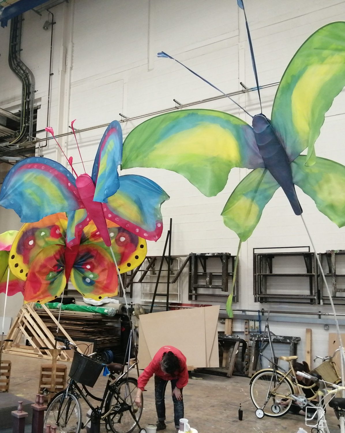 Large, colourful butterfly decorations hang from the ceiling in a workshop.