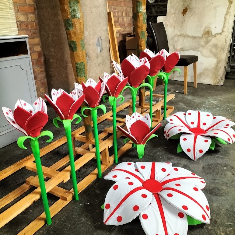Colourful decorative flowers with red petals and green stems, arranged in a warehouse setting.