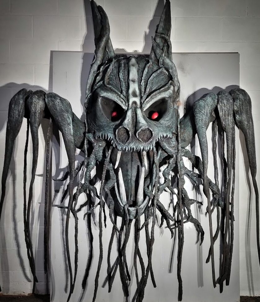A large, eerie mask with red eyes and long, tentacle-like extensions.