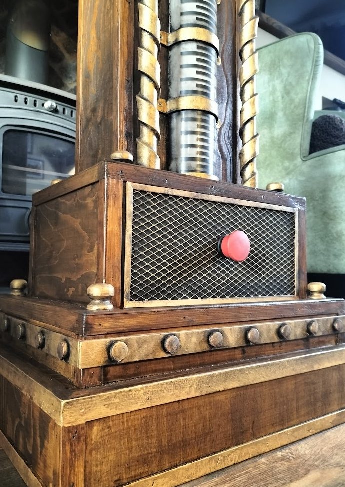 A vintage-style wooden machine with a red button and metal details.